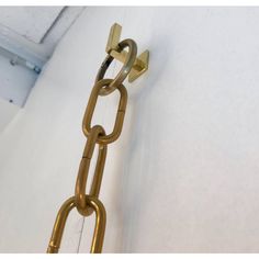 a gold chain hanging from the side of a white wall