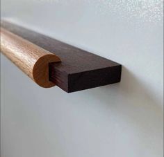 a close up of a piece of wood on a white wall with a wooden edge