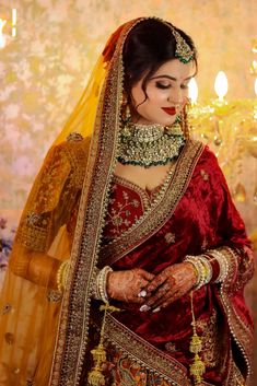 a woman in a red and gold bridal outfit with her hands on her chest