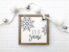 a sign that says let it snow hanging on a brick wall