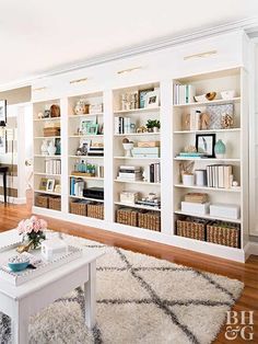 a living room filled with lots of white furniture and bookshelves full of books