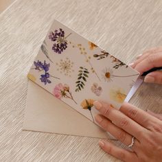 a woman is cutting paper with scissors on a piece of paper that has flowers all over it