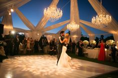 a bride and groom sharing their first dance under the chandelier at their wedding reception