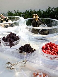 several bowls filled with different types of food on top of a white table covered in wine bottles