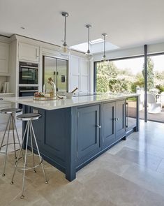 a large kitchen with an island and two stools in front of the counter top