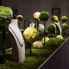 the display is filled with green and white flowers in vases, trees, and sculptures