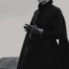 black and white photograph of a woman wearing a long coat with gloves on her hands