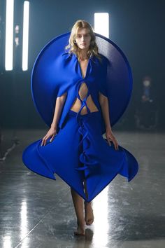 a model walks down the runway in a blue dress with an open back and cut out sides