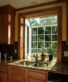 a kitchen with wooden cabinets and granite counter tops, an open window over the sink