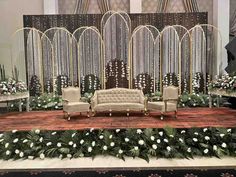 a stage set up for a wedding ceremony with couches, chairs and flowers on the floor