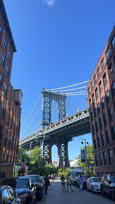 people are walking on the sidewalk in front of some buildings and a bridge over water