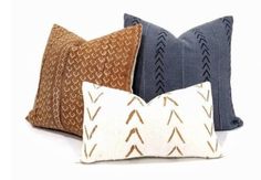 three decorative pillows with arrows on them, one brown and the other blue in different colors