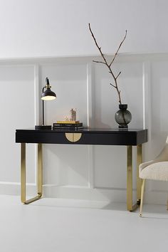 a table with a lamp and some books on it next to a chair in a room