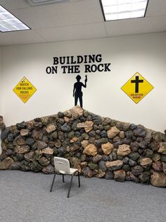 a man standing on top of a pile of rocks next to a sign that says building on the rock