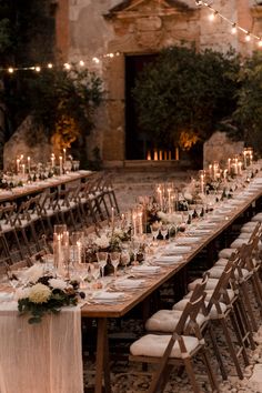 a long table is set up with candles and place settings for an outdoor dinner party