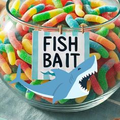 a glass bowl filled with colorful candy and a sign that says fish bait on it