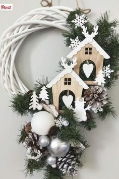 a wreath with a birdhouse and snowflakes hanging from it's side