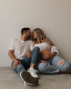 a pregnant couple sitting on the floor together