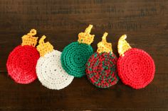 crocheted christmas ornaments are lined up on a wooden table with one red, white and green ornament