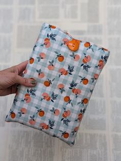 a person holding an orange and white checkered bag with buttons on it's side