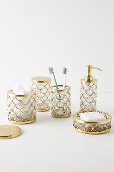 the bathroom accessories is gold and has white designs on it, along with a toothbrush holder