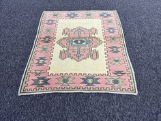 a pink and blue rug on the floor in an empty room with dark carpeting