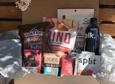 a box filled with lots of different types of food and drinks on top of a wooden table