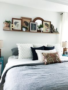 a bed with pillows and pictures on the wall above it, along with other decor