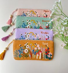 four embroidered pouchs with tassels and flowers on them sitting next to each other