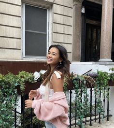 a woman is walking down the street with a pink blanket over her shoulder and smiling