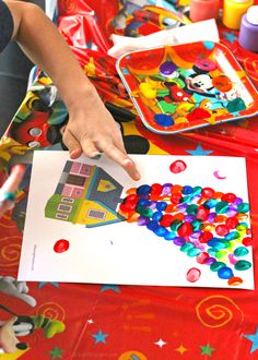 a child's hand is pointing at a paper with colorful candies on it