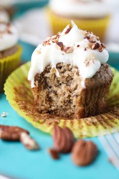 a cupcake with white frosting and pecans is on a green paper plate