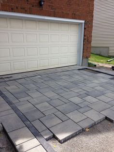 a driveway that has been laid out in front of a brick building with two garage doors