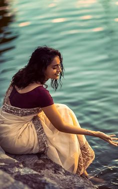 a woman sitting on the edge of a body of water