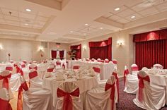 the banquet room is set up with white linens and red sashes