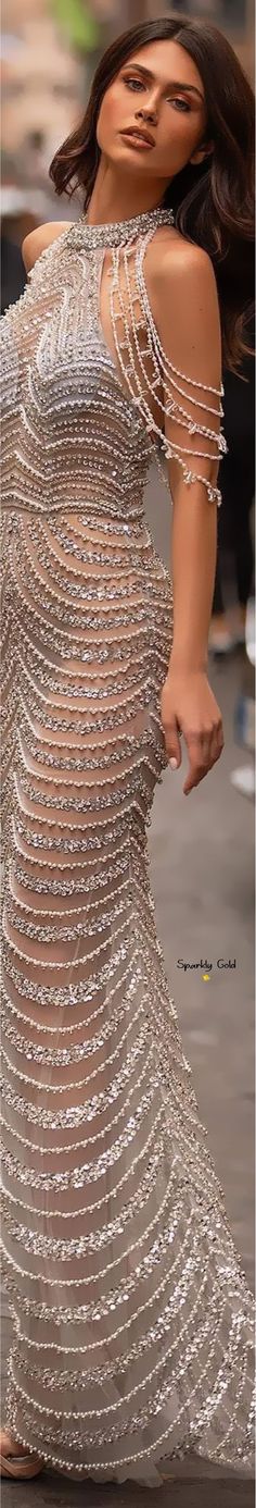 a woman is walking down the street wearing a dress made out of beads and chains