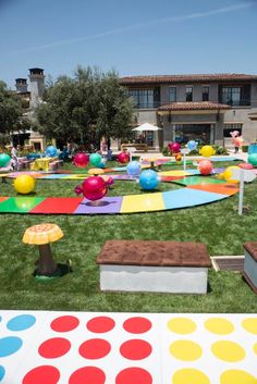 an outdoor play area with lots of different colored circles and dots on the grass, in front of a large building