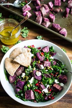 a white bowl filled with salad and pita chips on top of a wooden table