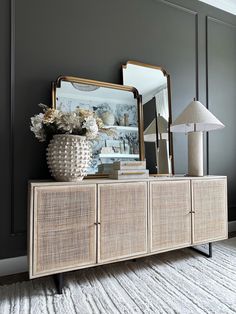 a large mirror sitting on top of a wooden cabinet next to a vase with flowers