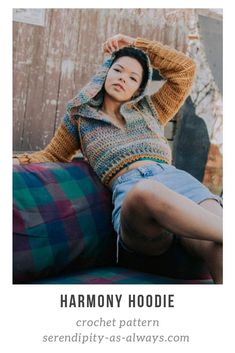 a woman sitting on top of a couch wearing a hoodie and denim shorts with text overlay that reads harmony hoodie crochet pattern