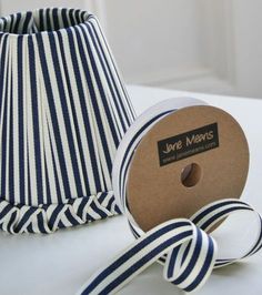 a roll of blue and white striped ribbon next to a lamp shade