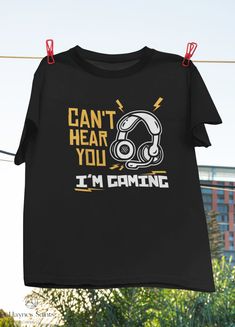 "Product: Can't Hear You I'm Gaming Funny Video Gamer Vintage T-Shirt, Gaming Shirt, Headphone Shirt, Gaming Shirt, Gamer Gift Shirt 💫 Welcome to our store! ✔️ PRODUCTS DETAIL: ▸ Available ALL types of clothing you NEED (8 types from kid to adult, hoodies, sweatshirts, tanktop,..) ▸ Light & Soft cotton fabric (Some colours contain polyester). ▸ High-quality Direct To Garment printing, guaranteed not to wash off or fade. ▸ Fit T-shirts, perfect gift idea for your family, friends... ✔️ SIZING: See size guide in gallery for exact measurements. If you want more of a tight ladies fit, we suggest going down one size. If not, take your normal size. ✔️ CUSTOM AND PERSONALIZED ORDERS: ▸ You can request a custom change on any of our products. ▸ You can give us your idea, and we will make a brand ne Black Gamer T-shirt With Letter Print, Gamer Graphic Print Short Sleeve Tops, Black Short Sleeve Gamer Tops, Black Gamer Top With Funny Text, Black Gamer T-shirt With Screen Print, Gamer T-shirt With Screen Print And Crew Neck, Gamer Style Short Sleeve Tops With Funny Text, Gamer Style Cotton T-shirt With Letter Print, Black Gamer T-shirt With Graphic Print