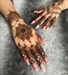 two hands with henna tattoos on them, one is showing off the intricate design