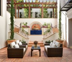 an outdoor living area with wicker furniture and potted plants