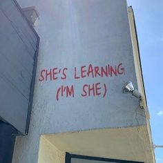 graffiti on the side of a building that says she's learning i'm she