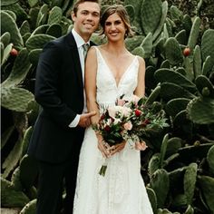 a bride and groom posing for a photo in front of cacti at their wedding