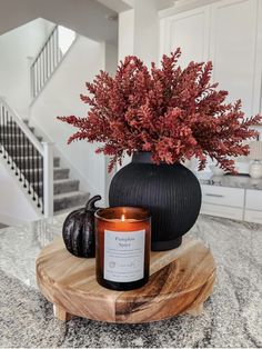 a candle sits on a table next to a vase with flowers in it and a pumpkin