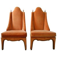 a pair of orange chairs sitting next to each other on top of a white background