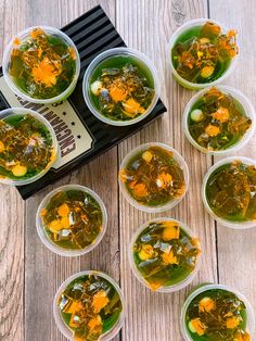 several cups filled with soup sitting on top of a wooden table next to a book