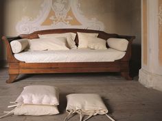 a wooden bed with pillows on it in a room that is painted gold and white